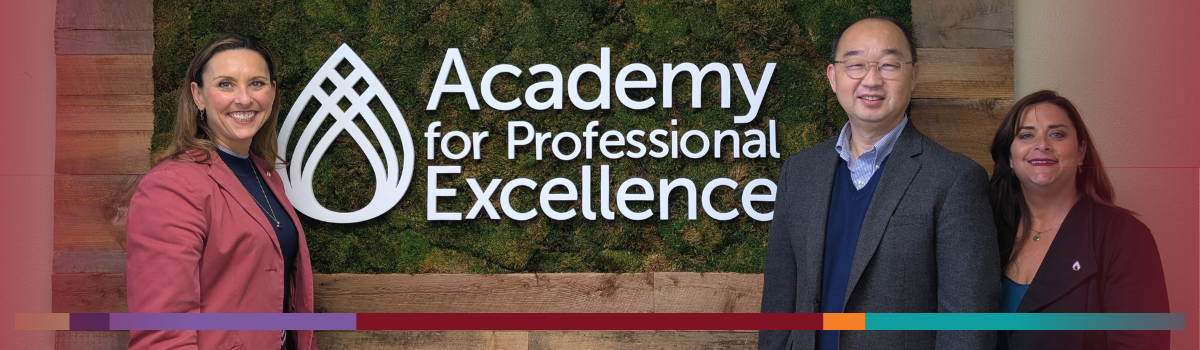 Image of Kim Giardina, Jong Won Min, and Jennifer Tucker-Tatlow in front of the Academy for Professional Excellence office logo.